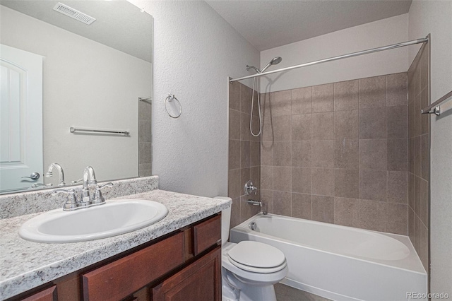 full bathroom with toilet, vanity, a textured ceiling, and tiled shower / bath