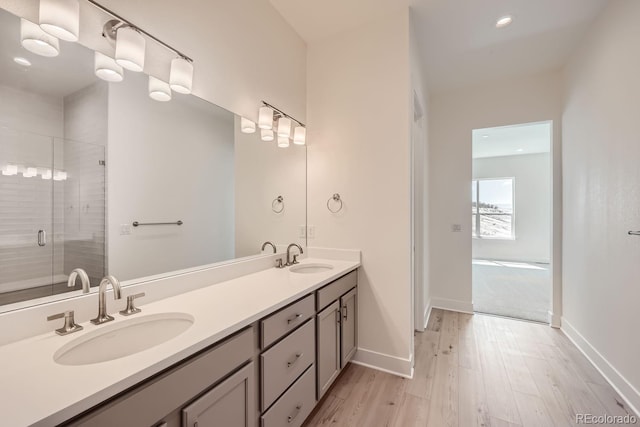 bathroom with wood-type flooring, a shower with shower door, and vanity