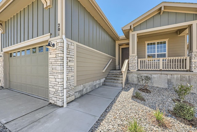 entrance to property featuring covered porch, board and batten siding, concrete driveway, and brick siding