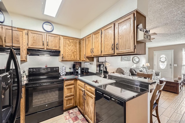 kitchen with black appliances, kitchen peninsula, sink, and a textured ceiling