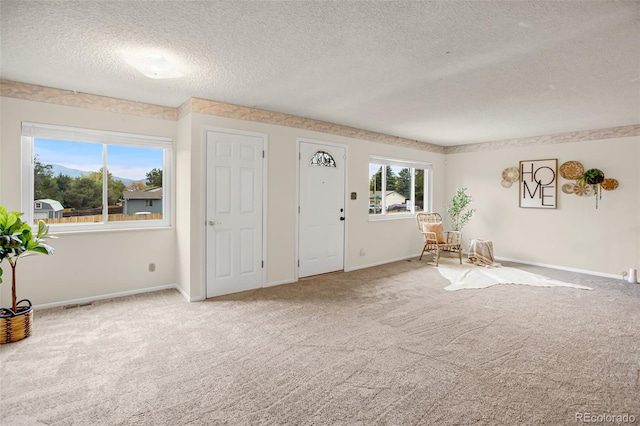 carpeted foyer featuring a textured ceiling