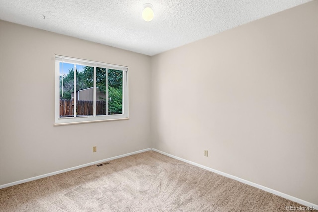 spare room featuring carpet flooring and a textured ceiling