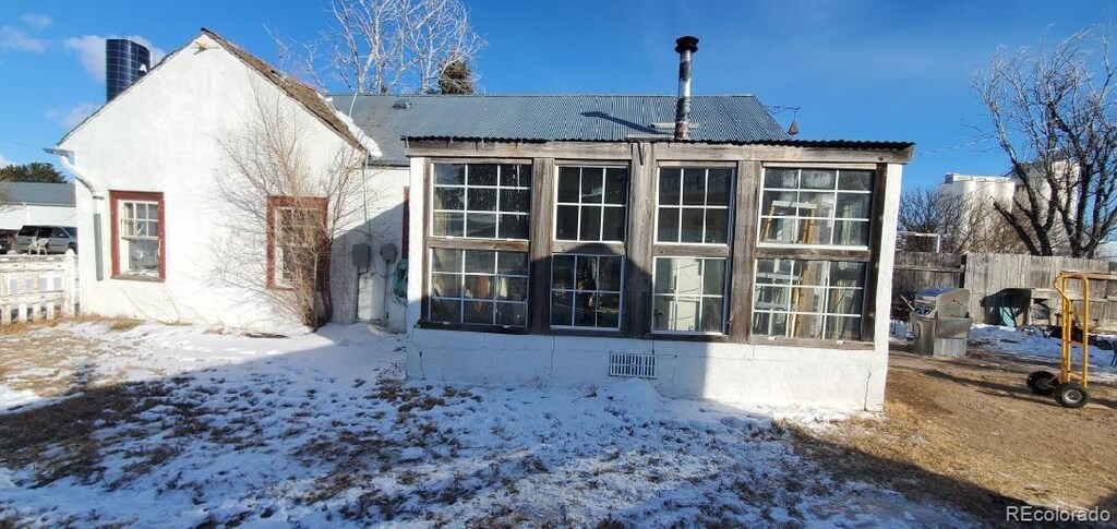 snow covered back of property with fence and a chimney