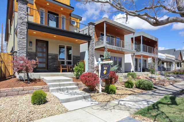 contemporary home with covered porch, stone siding, and stucco siding