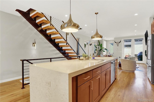 kitchen featuring a sink, open floor plan, recessed lighting, light wood-style floors, and hanging light fixtures