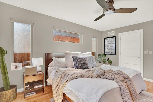 bedroom with baseboards, visible vents, light wood finished floors, and ceiling fan