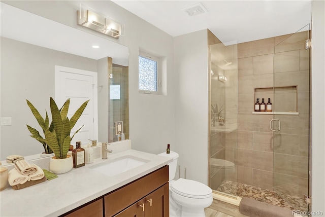 bathroom with visible vents, vanity, toilet, and a shower stall