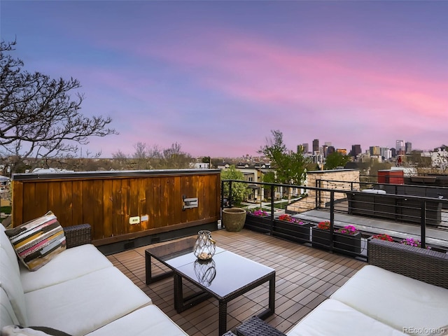 patio terrace at dusk featuring a balcony, a city view, and outdoor lounge area