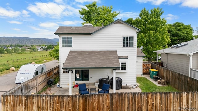 8544 S Upham Way, Littleton, CO 80128 - back of house with a fenced backyard, a shingled roof, a patio, and a mountain view