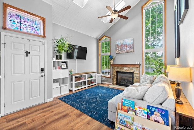 8544 S Upham Way, Littleton, CO 80128 - living room featuring ceiling fan, wood finished floors, a stone fireplace, healthy amount of natural light, and high vaulted ceiling
