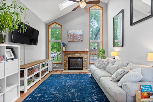 8544 S Upham Way, Littleton, CO 80128 - living area featuring vaulted ceiling, a ceiling fan, wood finished floors, a skylight, and a stone fireplace