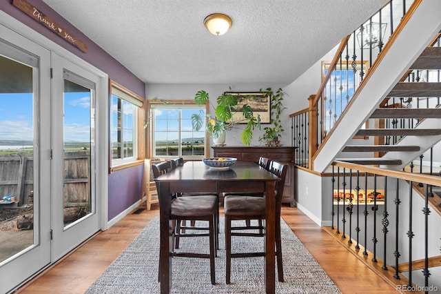 8544 S Upham Way, Littleton, CO 80128 - dining space with a textured ceiling, light wood-style floors, and stairs