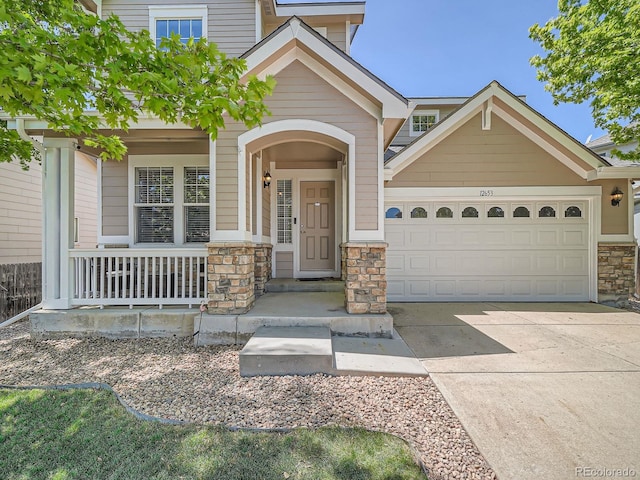 12653 Jersey Cir E, Thornton, CO 80602 - view of front facade featuring stone siding, covered porch, concrete driveway, and a garage