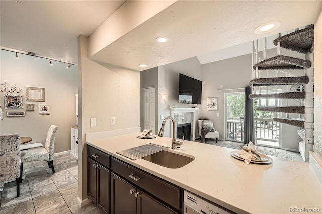 10872 W Evans Ave Unit 3D, Lakewood, CO 80227 - kitchen featuring a sink, light countertops, a tiled fireplace, open floor plan, and a peninsula