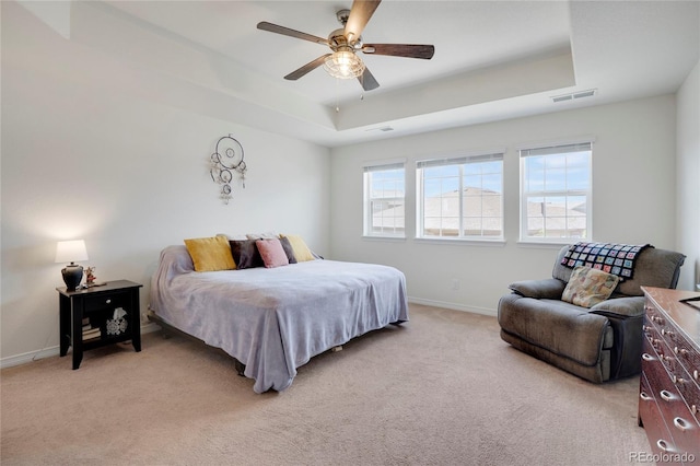 bedroom featuring a raised ceiling, light colored carpet, baseboards, and ceiling fan