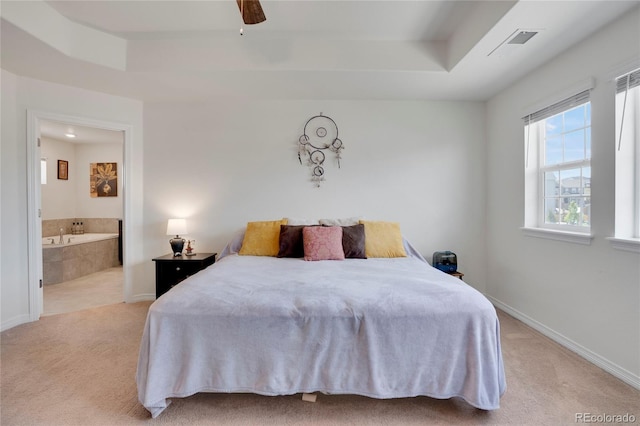 bedroom with light carpet, connected bathroom, baseboards, and a raised ceiling