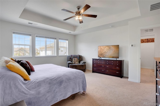 bedroom featuring a tray ceiling, light colored carpet, baseboards, and ceiling fan