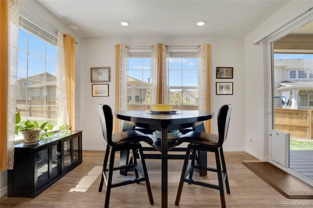 dining space with baseboards, light wood-type flooring, and recessed lighting