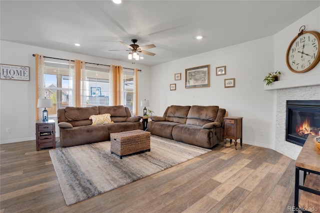 living area with wood finished floors, ceiling fan, recessed lighting, a fireplace, and baseboards
