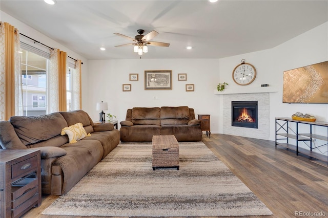 living room with wood finished floors, ceiling fan, a glass covered fireplace, and recessed lighting