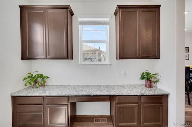 kitchen featuring light stone counters and dark brown cabinets