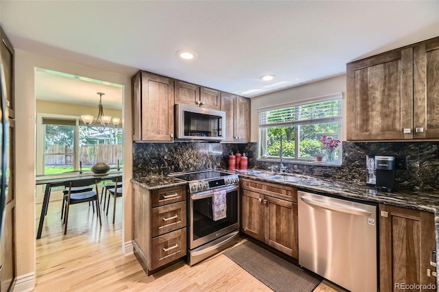 6338 S Oneida Ct, Centennial, CO 80111 - kitchen featuring appliances with stainless steel finishes, dark stone counters, light wood-type flooring, a sink, and backsplash