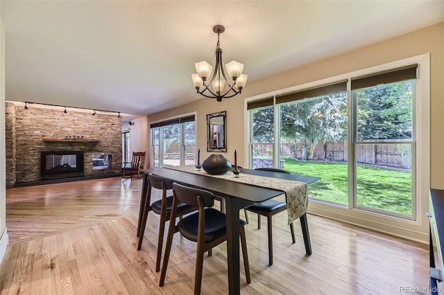 6338 S Oneida Ct, Centennial, CO 80111 - dining space with rail lighting, a stone fireplace, a chandelier, and light wood-style floors