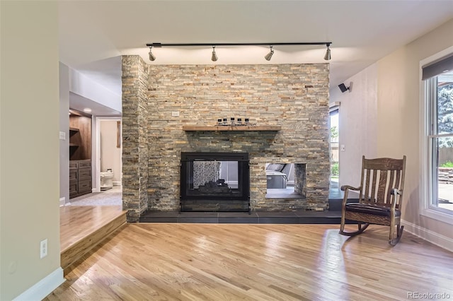 6338 S Oneida Ct, Centennial, CO 80111 - living room with rail lighting, wood finished floors, a stone fireplace, and baseboards