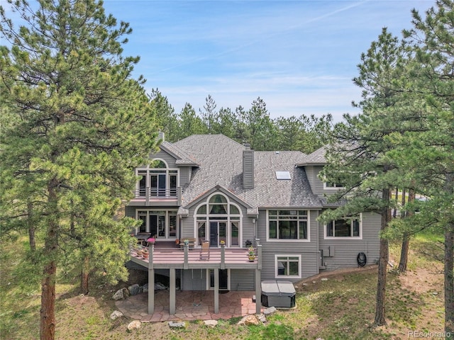 29433 Firethorne Ct, Evergreen, CO 80439 - back of house featuring a covered hot tub, a patio area, roof with shingles, a balcony, and a wooden deck