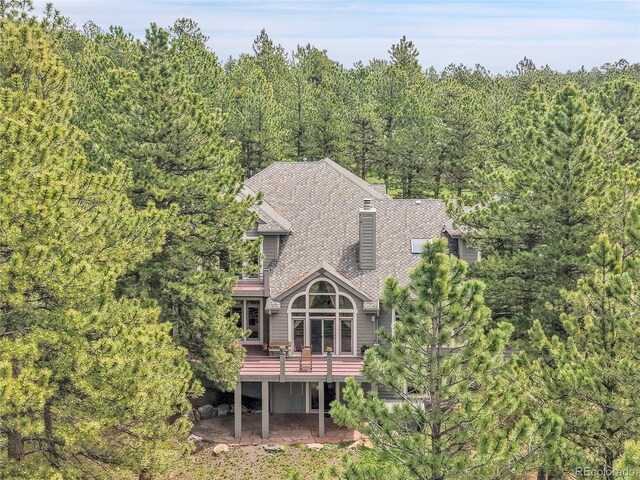 29433 Firethorne Ct, Evergreen, CO 80439 - back of house with a deck, a chimney, a forest view, and roof with shingles