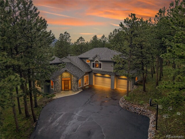 29433 Firethorne Ct, Evergreen, CO 80439 - view of front of home featuring asphalt driveway, stone siding, an attached garage, and roof with shingles