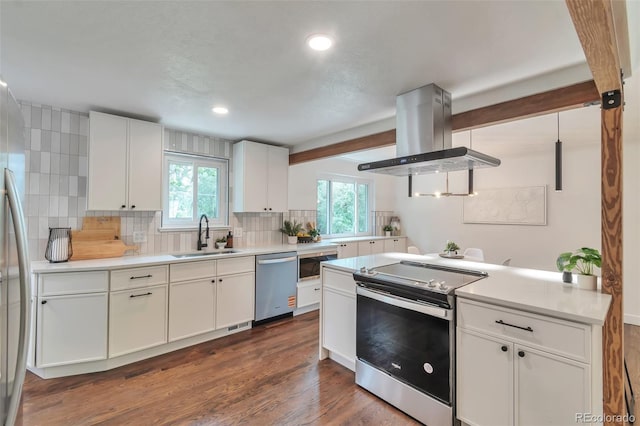 2598 Teller St, Lakewood, CO 80214 - kitchen with stainless steel appliances, island range hood, a sink, tasteful backsplash, and white cabinetry