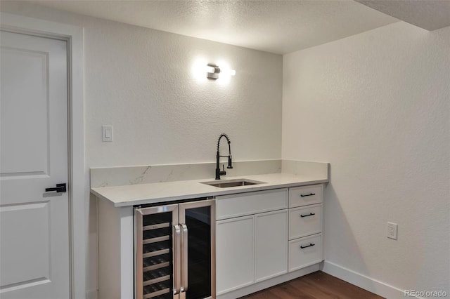 2598 Teller St, Lakewood, CO 80214 - indoor wet bar featuring beverage cooler, dark wood-style floors, baseboards, and a textured wall