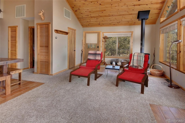 sitting room with a wood stove, carpet floors, wooden ceiling, and high vaulted ceiling