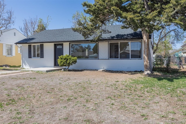 single story home with concrete block siding, roof with shingles, and fence