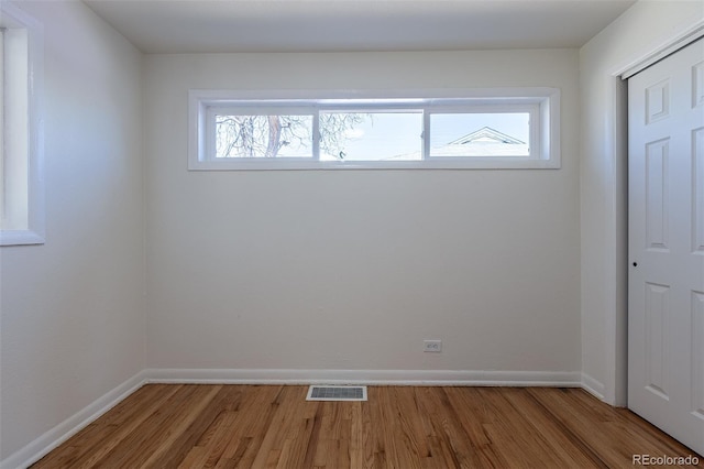 spare room featuring visible vents, baseboards, and wood finished floors