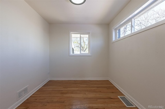 unfurnished room featuring visible vents, baseboards, and wood finished floors