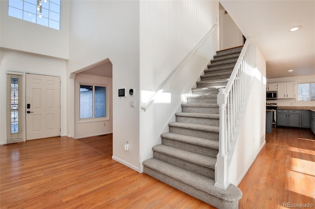 entryway featuring a towering ceiling and light wood-type flooring