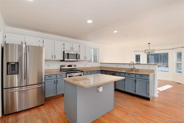 kitchen featuring sink, decorative light fixtures, a center island, light hardwood / wood-style flooring, and stainless steel appliances