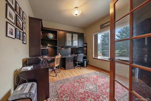 home office with light wood-type flooring and french doors