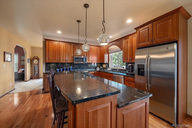 kitchen featuring stainless steel appliances, decorative backsplash, pendant lighting, a center island, and sink