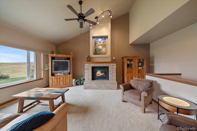 carpeted living room featuring a brick fireplace, vaulted ceiling, ceiling fan, and track lighting