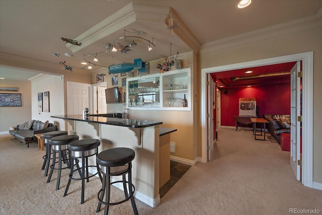 kitchen featuring carpet, kitchen peninsula, a breakfast bar, crown molding, and rail lighting