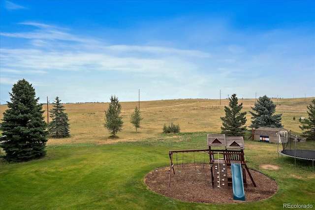 view of yard featuring a trampoline, a rural view, a playground, and a storage shed