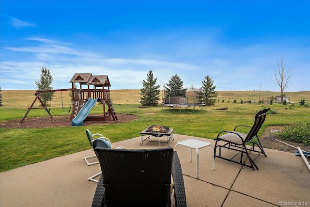 view of patio / terrace featuring a playground, a rural view, a fire pit, and a trampoline