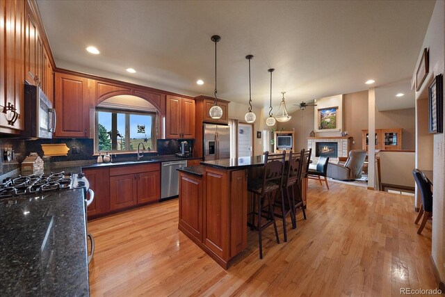 5861 E Valley Hi Dr, Parker, CO 80138 - kitchen with appliances with stainless steel finishes, light wood finished floors, a kitchen bar, tasteful backsplash, and a kitchen island