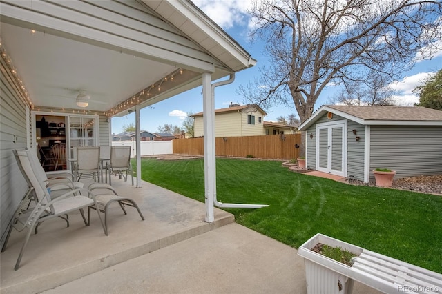 view of patio with outdoor dining area, a fenced backyard, a shed, and an outbuilding