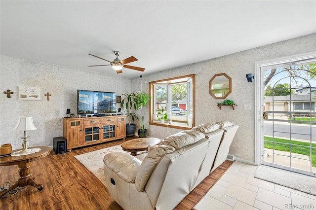 living room featuring a ceiling fan, a wealth of natural light, and wallpapered walls