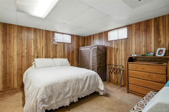 bedroom with light colored carpet, wooden walls, and multiple windows