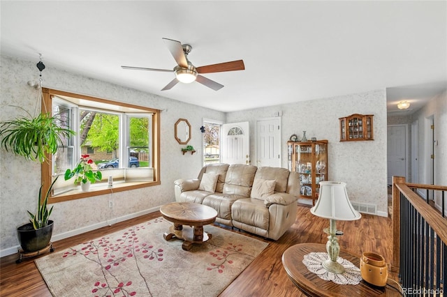 living room featuring baseboards, ceiling fan, and wood finished floors